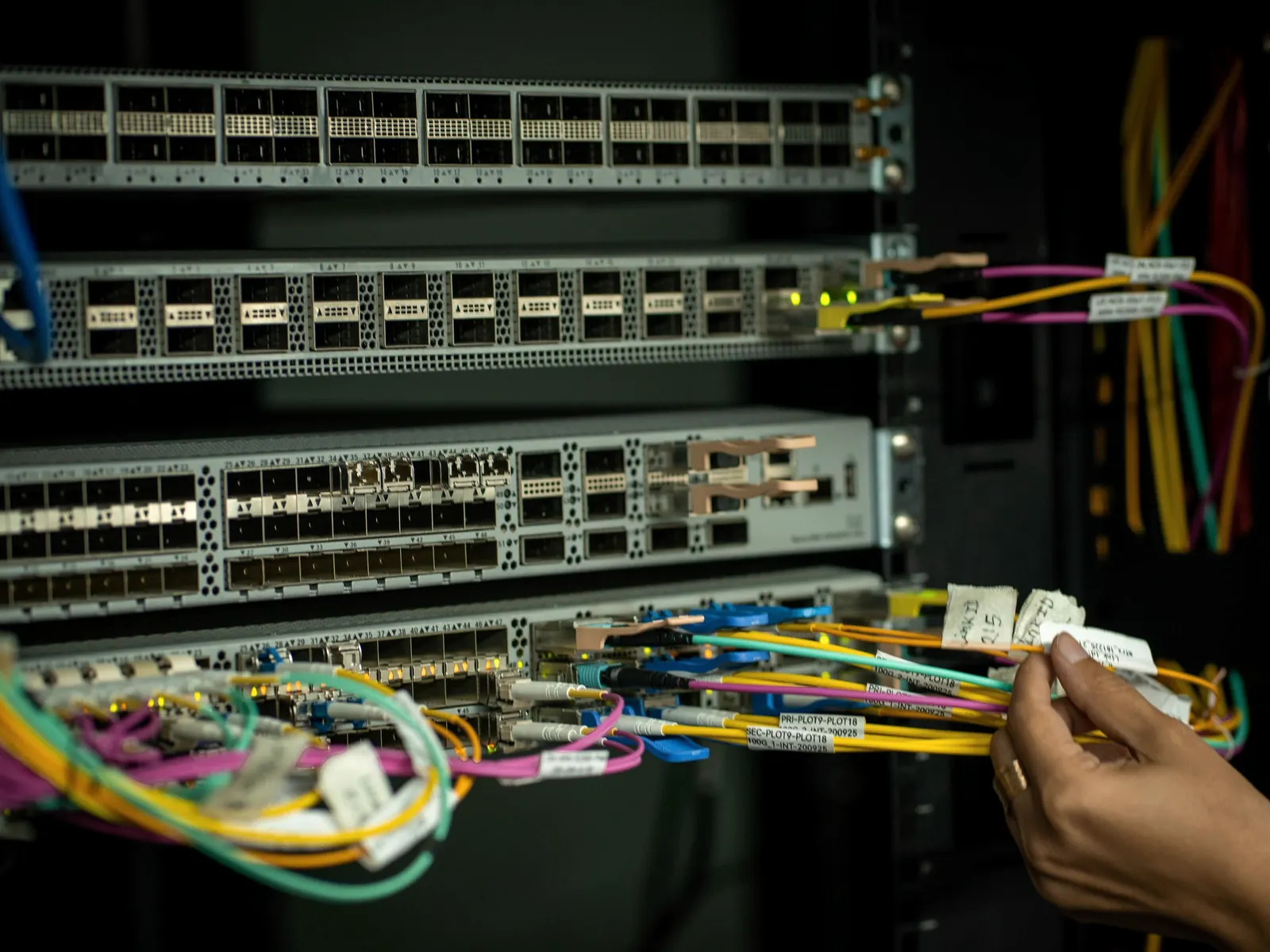 An engineer working on network cabling in an equipment rack